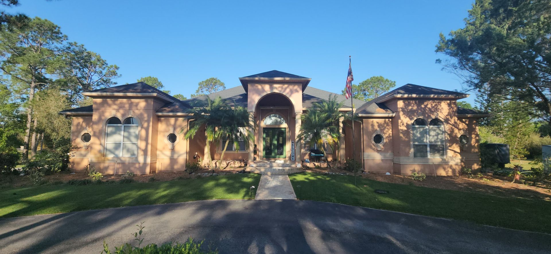 The back of a house with a covered porch and a white fence.