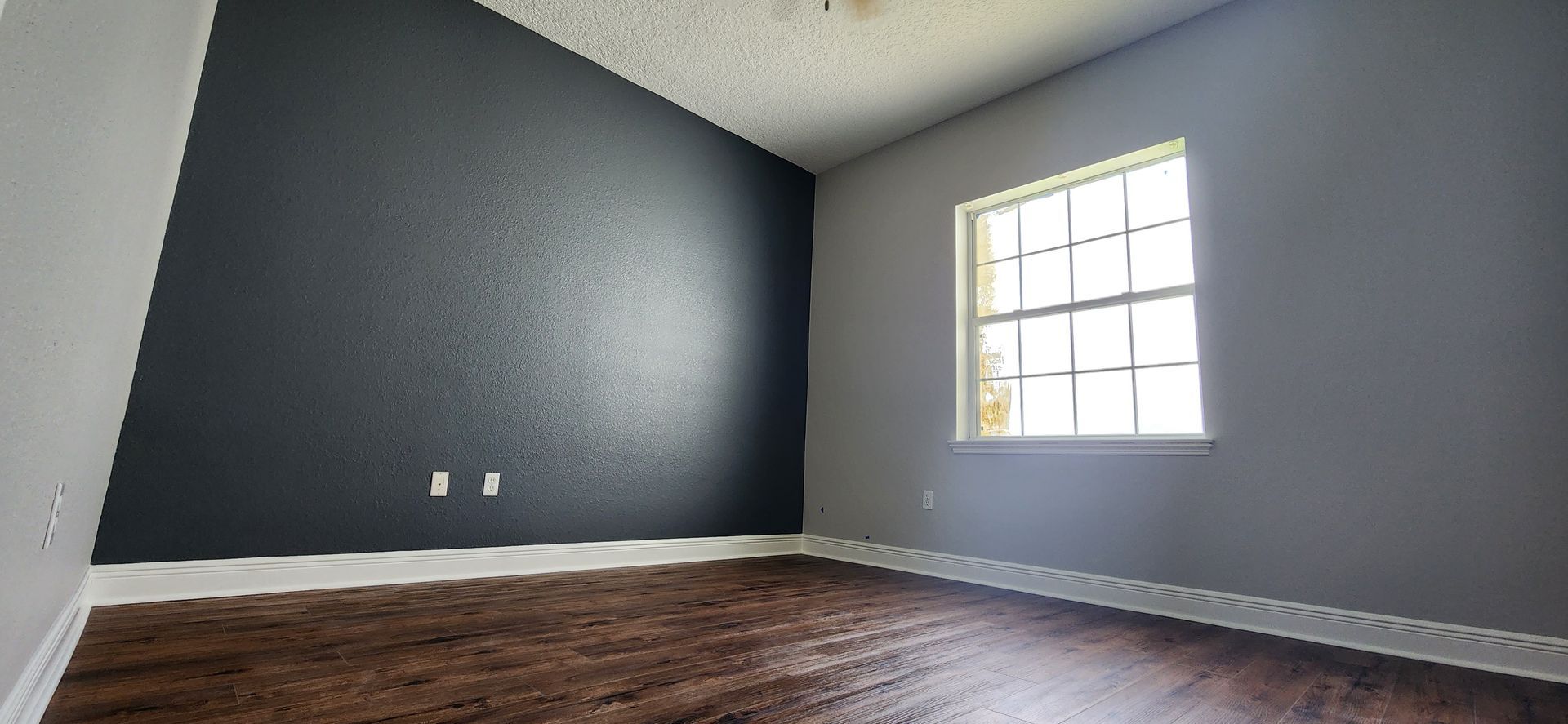 An empty room with a window and a black wall