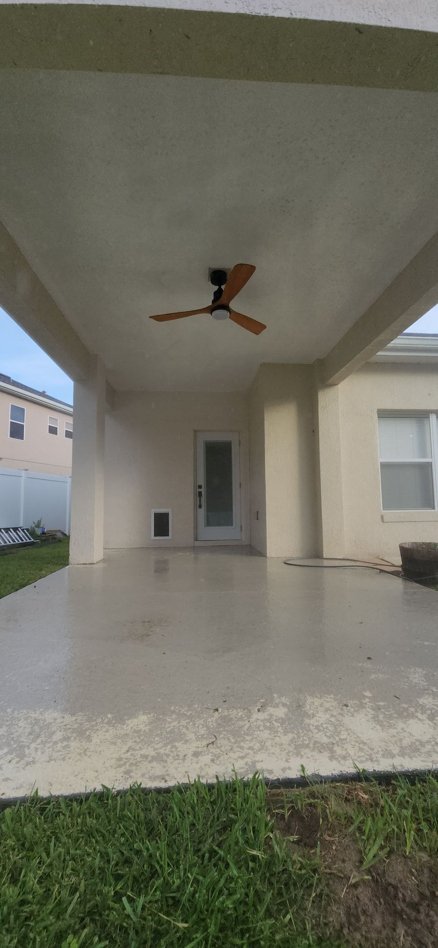 There is a ceiling fan on the patio of a house.