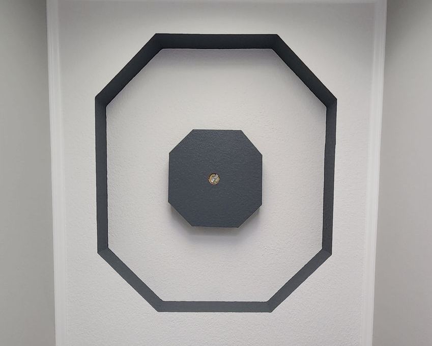 A white wall with a black octagon on it