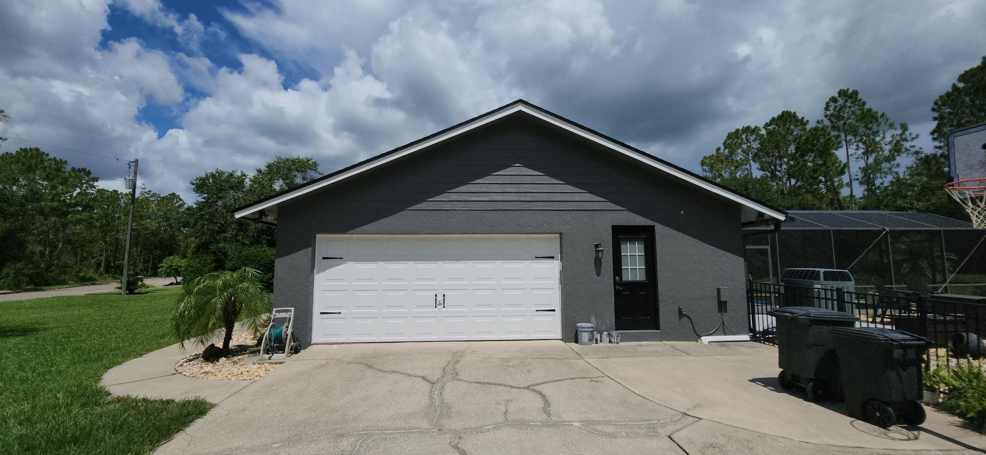 A gray house with a white garage door and a black door