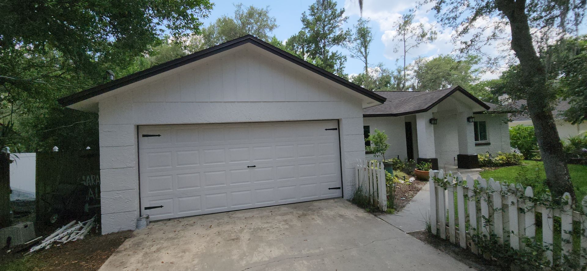 The back of a house with a covered porch and a white fence.