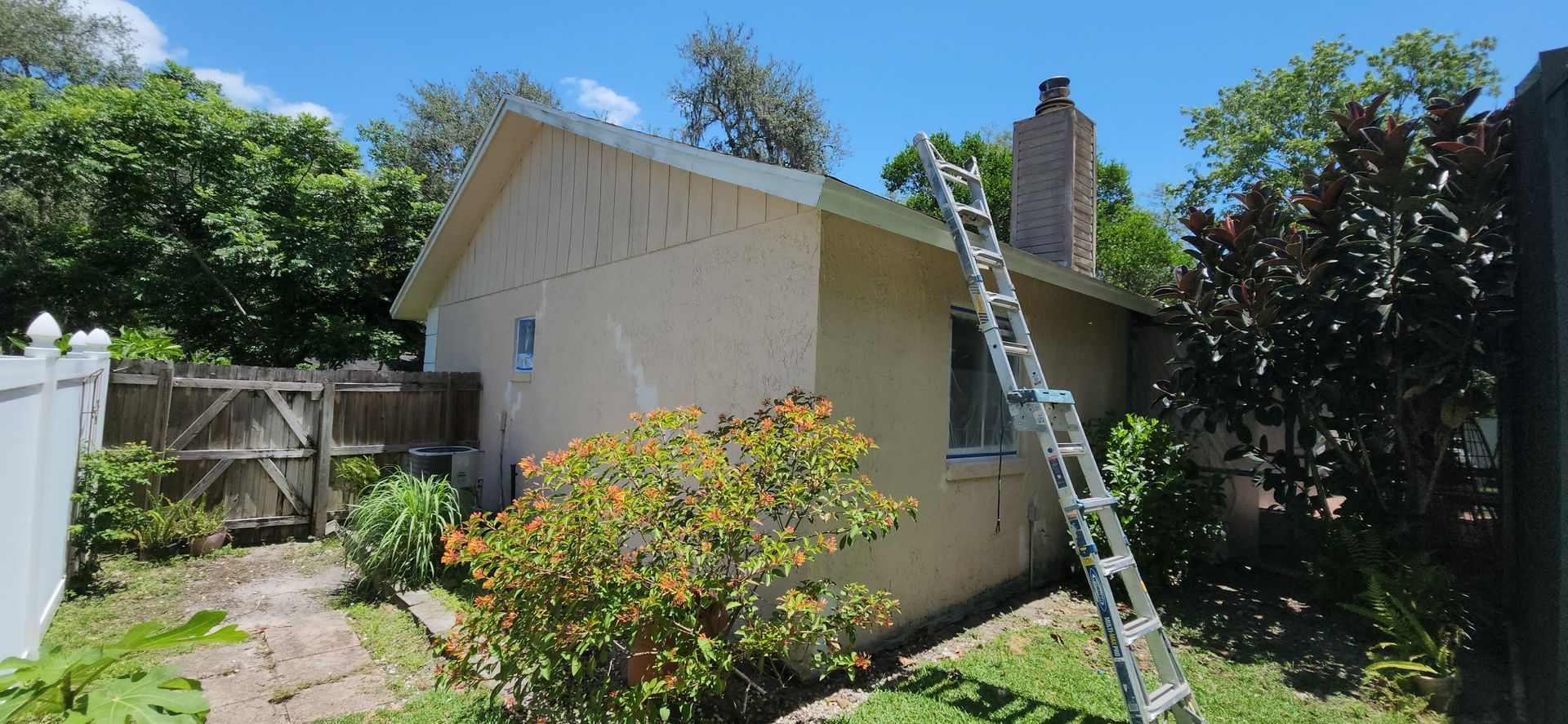 The backyard of a house with a covered patio and a large lawn.