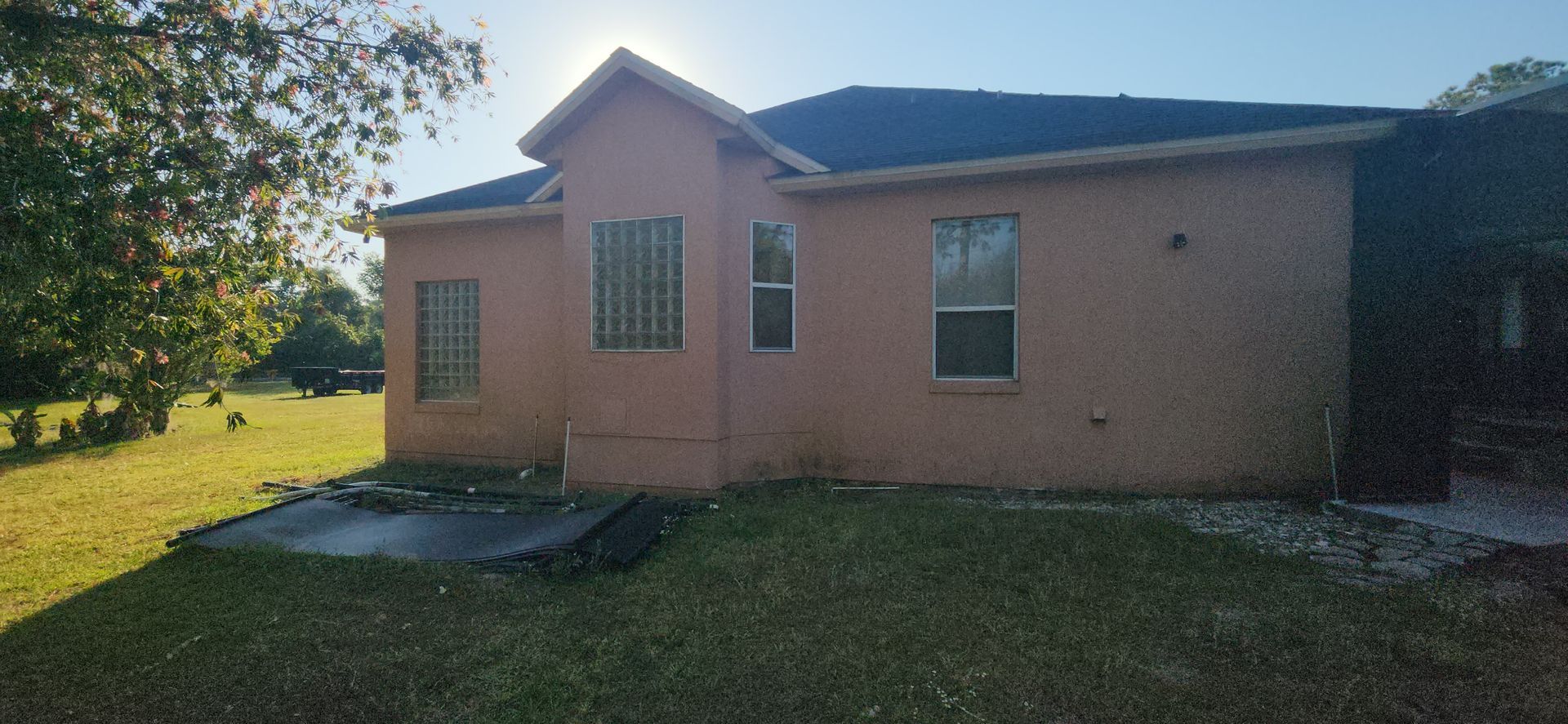 A house with a lot of windows is sitting on top of a lush green field.