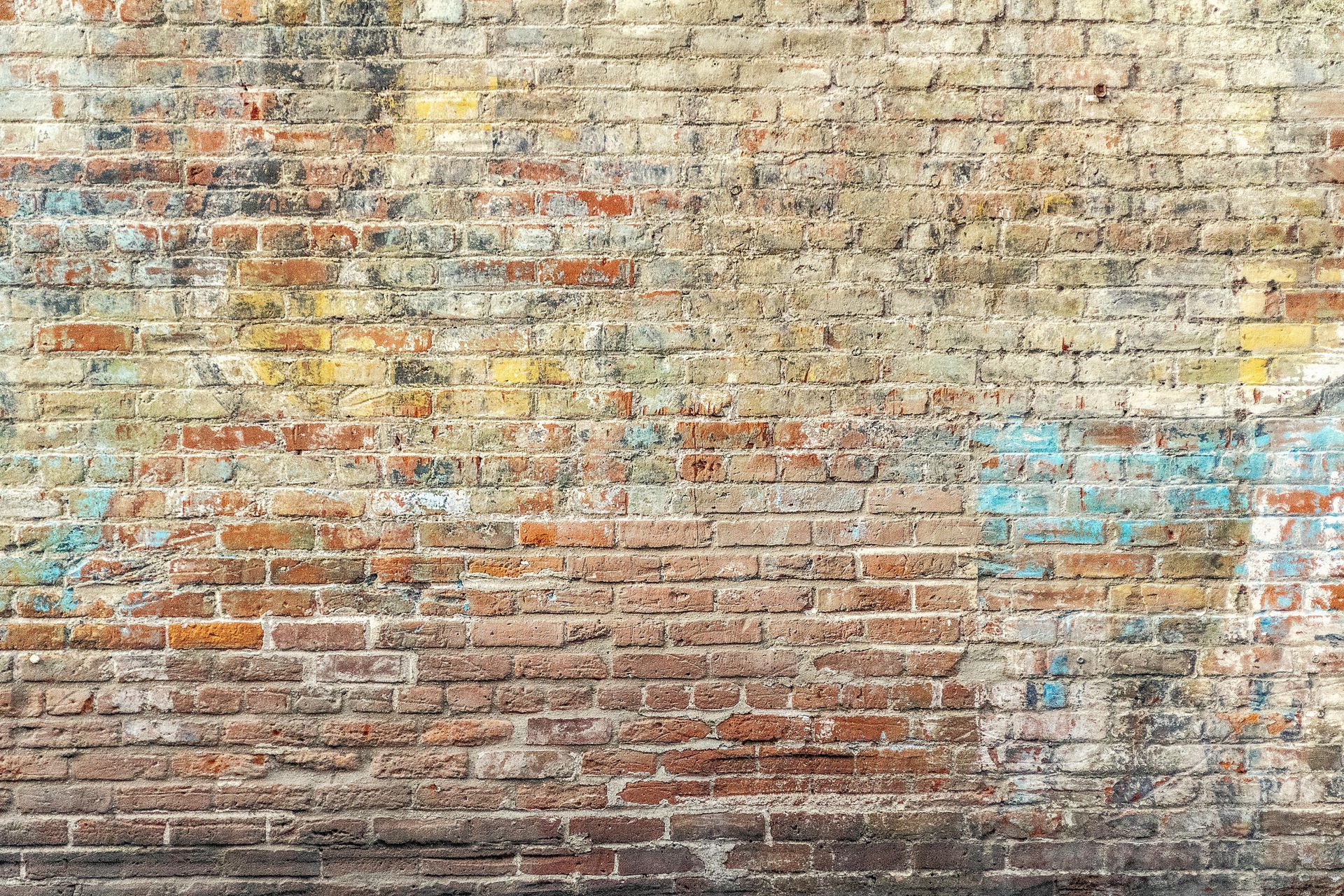 Weathered brick wall with faded blue and yellow paint splotches.