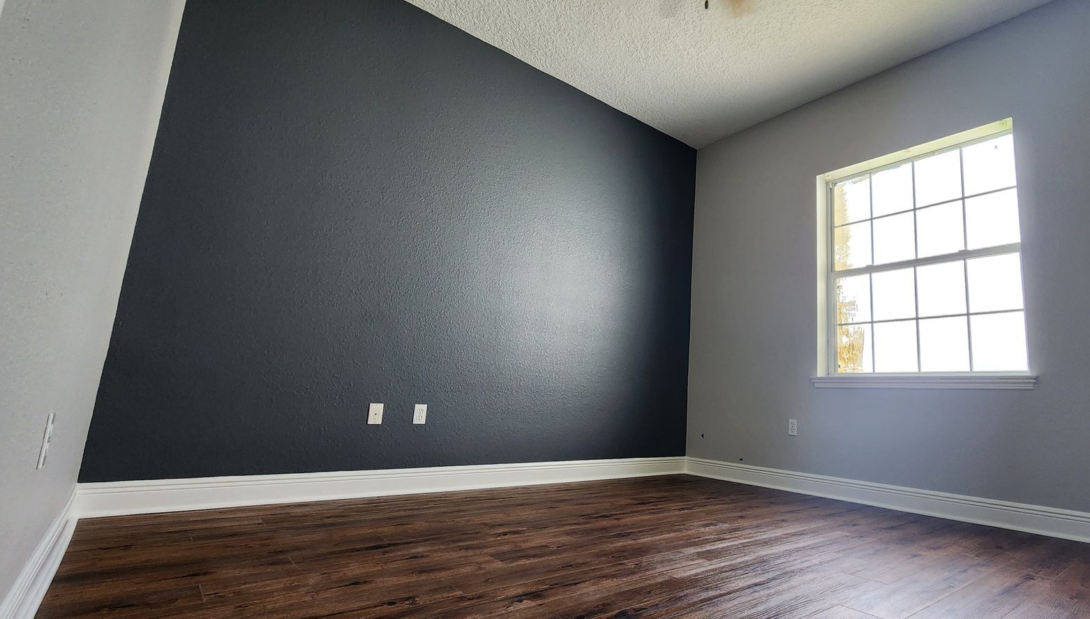 A large swimming pool is surrounded by a fence and a screened in area.